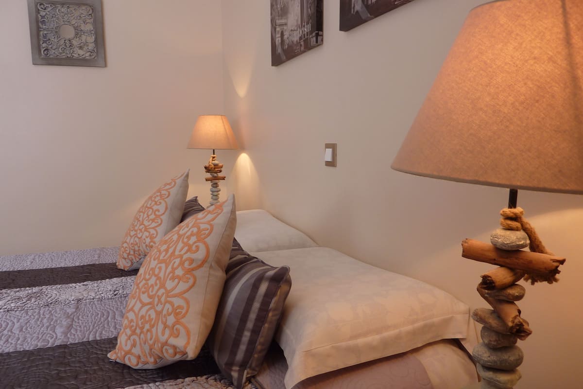 A neatly arranged bedroom with a bed, pillows, a bedside lamp, and a wall-mounted picture.