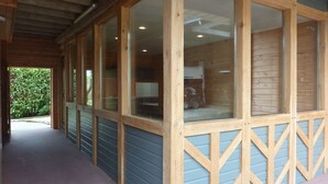 A covered corridor with wooden walls and large windows. - Domaine de la Hurel (Valambray)