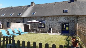 A stone building with a sloped roof, a barbecue area, and outdoor seating with umbrellas. - Spacious rural gite near Malestroit, Brittany - sleeps 6 (Ruffiac)