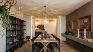 A dining area with a long wooden table, black chairs, a chandelier, and a bookshelf with decorative items. - Villa Sogno Adriatico (Civitanova Marche)