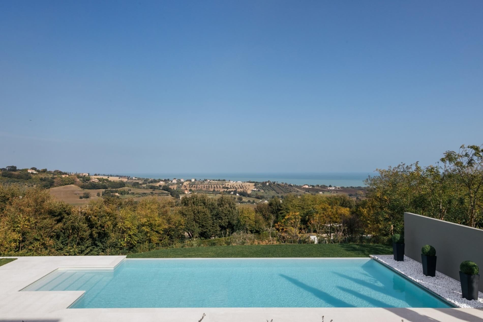 Uma piscina moderna com vista desobstruída para a paisagem ao redor e o horizonte distante.