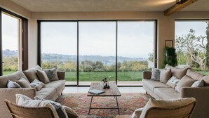 A spacious living area with two sofas facing a large sliding glass door, offering a view of a green landscape. - Villa Sogno Adriatico (Civitanova Marche)