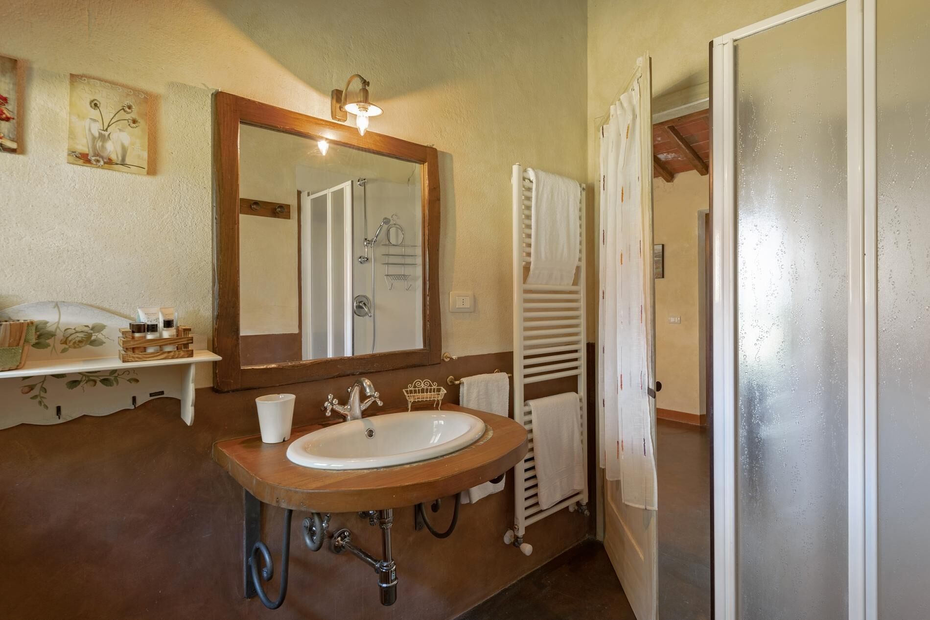 A bathroom with a wooden vanity, a large mirror, a sink, and a towel rack.