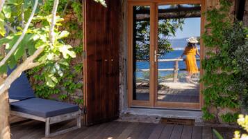 A wooden deck with a bench, a stone wall, and a view of the sea.