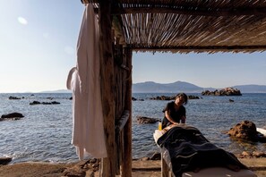 A beachside massage setup with a wooden structure, a towel, and a massage table by the water. - Villa Kirssis (Pietrosella)
