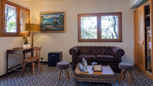 Una sala de estar con un sofá de cuero marrón, una mesa de centro de madera, una lámpara y un cuadro en la pared.
