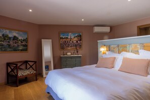 A bedroom with a large bed, a dresser, a bench, and two paintings on the wall. - Villa Kirssis (Pietrosella)