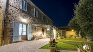 A stone building with a paved courtyard, outdoor seating, and potted plants. - Villa Margherita (Cortona)