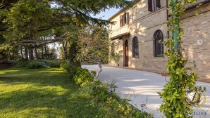 A historic building with a brick facade, arched windows, and a well-maintained lawn. - Villa Panperduto (Potenza Picena)