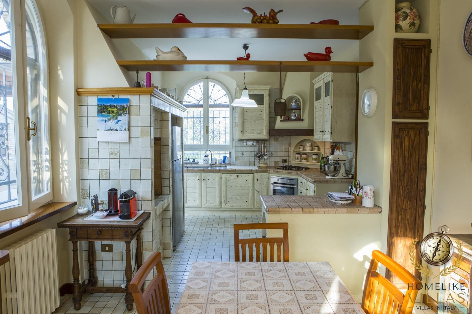 Cozinha com área de jantar, piso ladrilhado, armários de madeira e janela com vista.