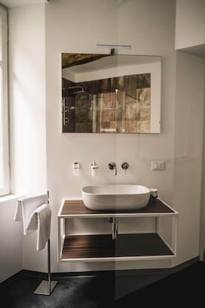 A modern bathroom with a freestanding sink, a large mirror, and a towel rack.