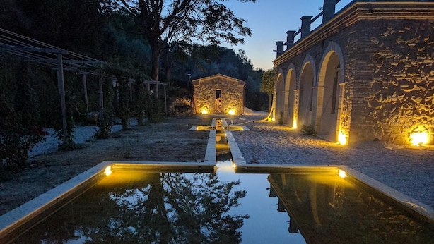 Un área de piscina al aire libre tranquila, con arquitectura de piedra e iluminación cálida.
