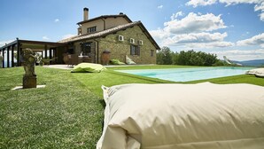 A stone house with a swimming pool, a covered patio, and a grassy lawn. - Villa Panorama (Monte Santa Maria Tiberina)