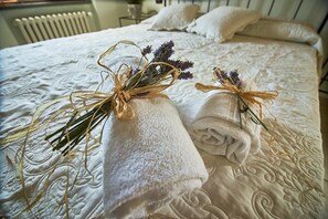 A neatly made bed with two rolled towels tied with dried flowers and twine, placed on a textured white bedspread. - Villa Panorama (Monte Santa Maria Tiberina)