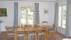 Un coin repas avec une table et des chaises en bois, un vase et un tableau accroché au mur.