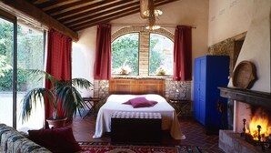 A cozy bedroom with a bed, a fireplace, and a large window with curtains. - Fienile (4+2) beautiful apartment with pool in Chianti between Florence and Siena (Tavarnelle Val di Pesa)