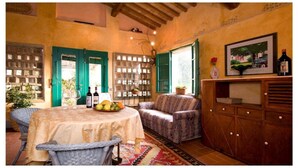 A cozy dining area with a round table, wicker chairs, and a patterned sofa. There is a wooden cabinet with drawers and a framed painting on the wall. - Fienile (4+2) beautiful apartment with pool in Chianti between Florence and Siena (Tavarnelle Val di Pesa)