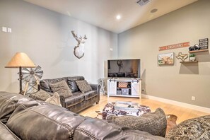 Una sala de estar con un sofá de cuero, una lámpara con forma de molino, una cabeza de ciervo montada en la pared, un televisor y un estante con objetos decorativos.