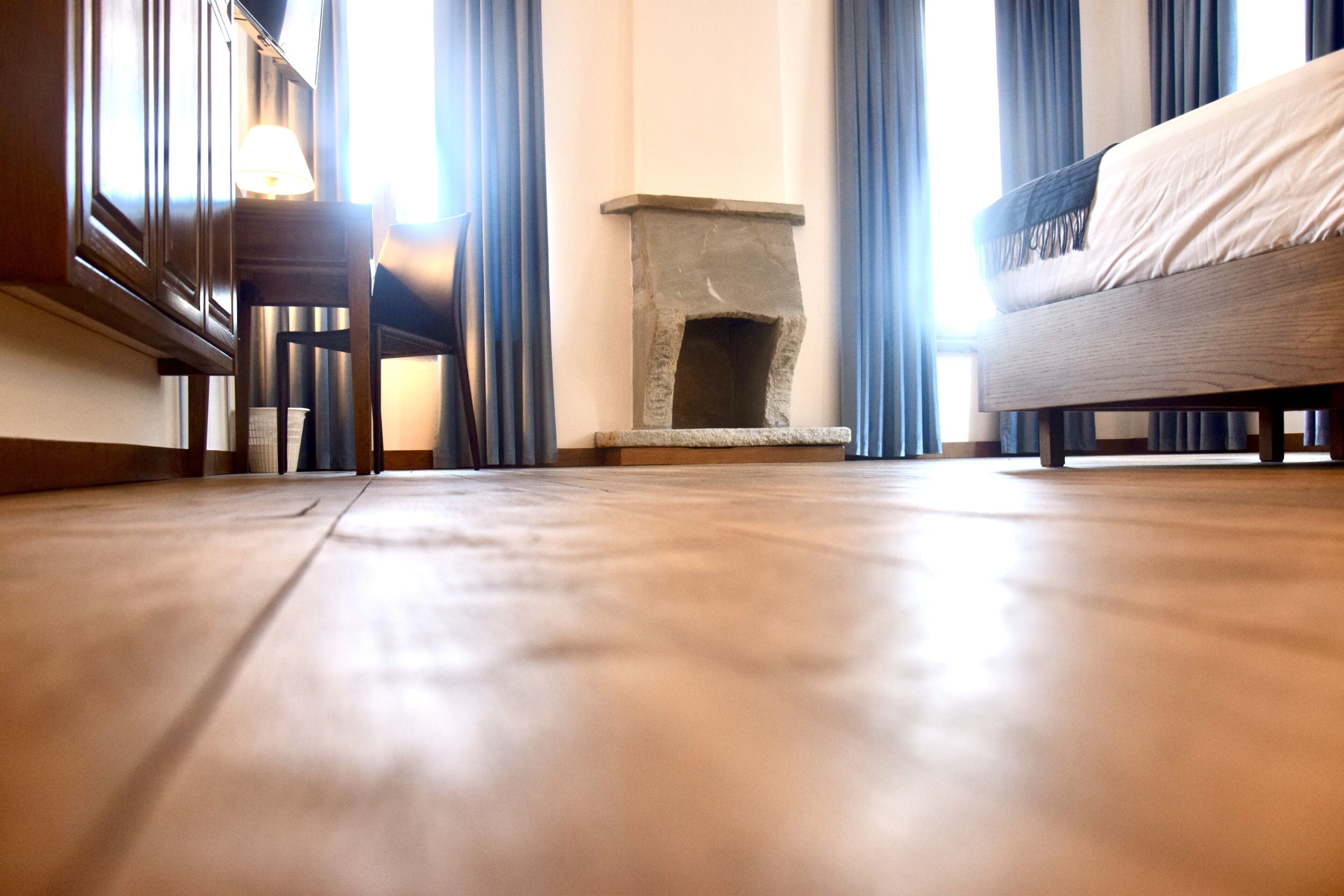 A room with a stone fireplace, a sofa, and a wooden floor.