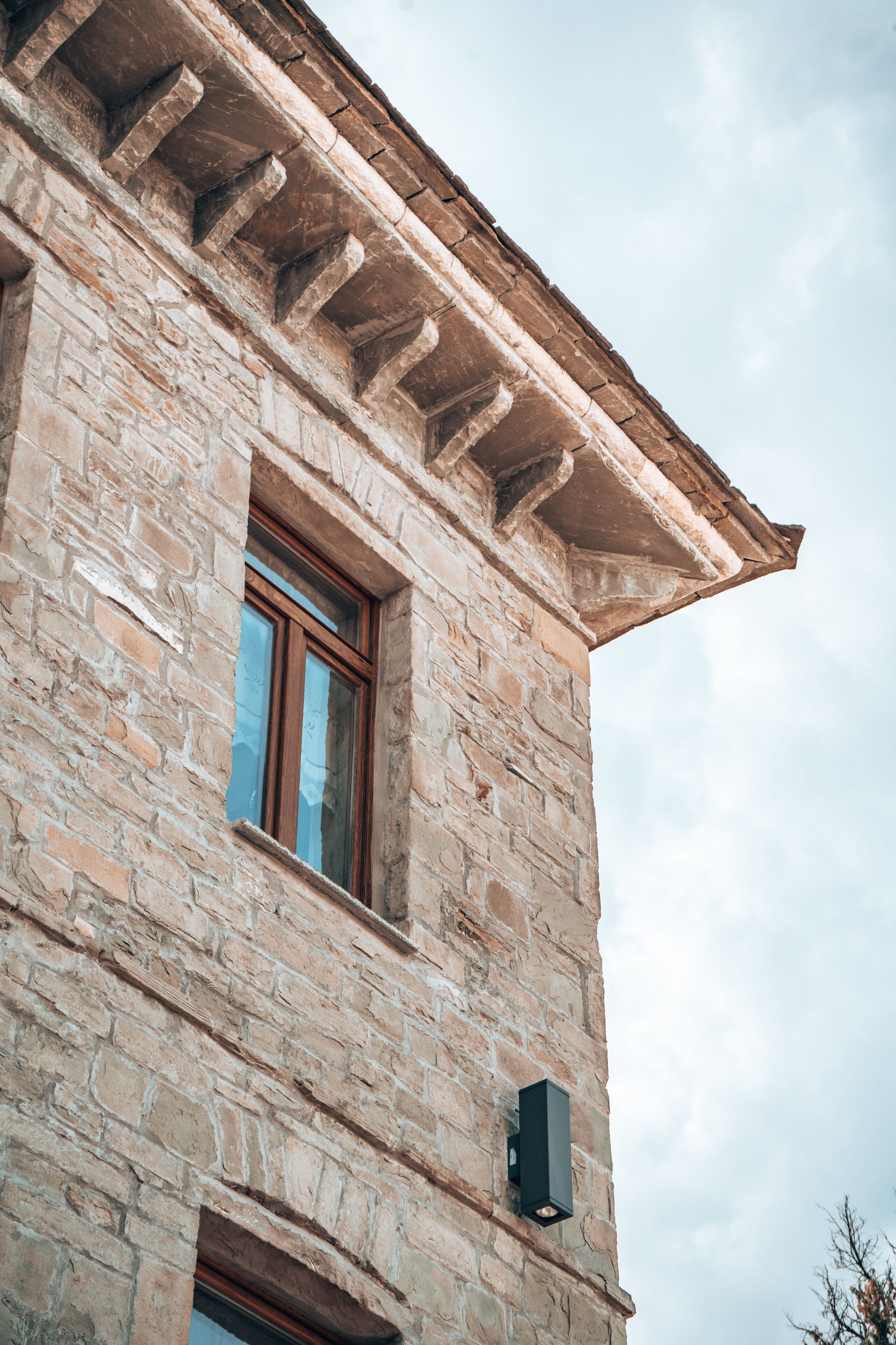 A stone building with a window and a small attached structure.