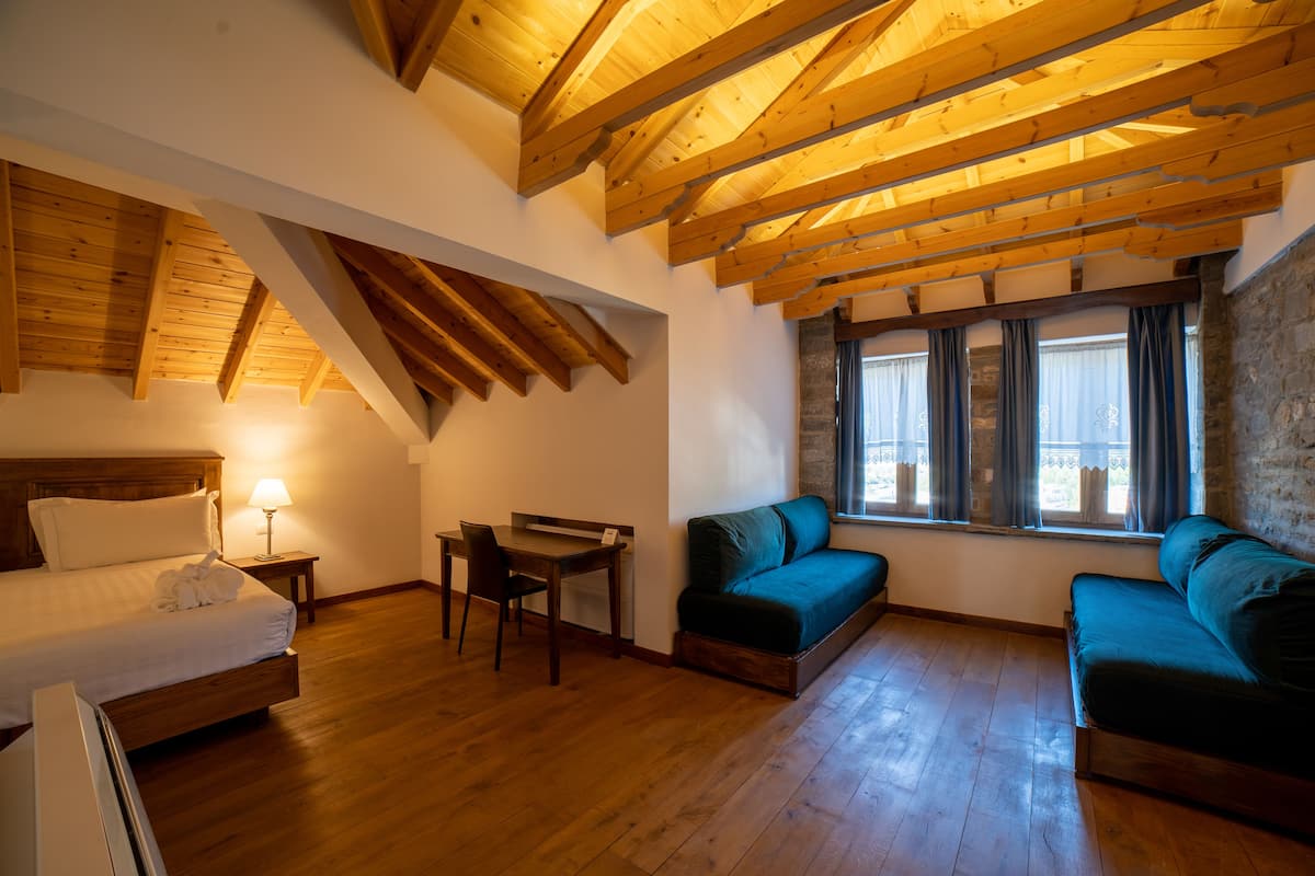 Una habitación con techo de madera, una cama, un escritorio y dos sofás.