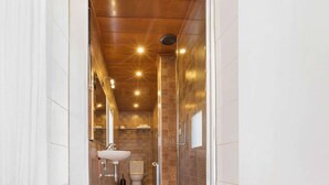 A narrow, well-lit bathroom with a wooden ceiling, a white sink, and a toilet. - Spectacular penthouse with terrace (Barcelona)