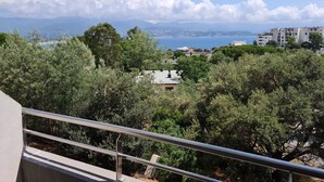 A balcony with a metal railing overlooking a coastal area with trees, buildings, and a clear sky. - Magnificent T2 parahotelier with 23m2 south-facing terrace and sea view (Ajaccio)