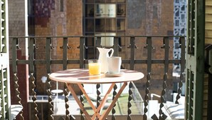 A small round table with a white pitcher and a glass of orange juice on a balcony with a metal railing. - Bright modernist apartment in Rambla Catalunya (Barcelona)