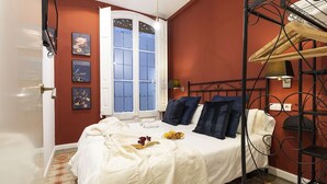 Un dormitorio con cama, ventana, estante en la pared y puerta.
