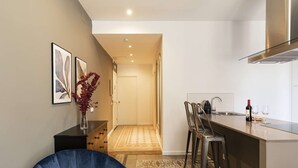 Una cocina moderna con barra, zona de estar y puerta a otra habitación.