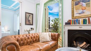 A room with a brown leather sofa, a fireplace, a telescope, and a painting. - Luxury and design in Rambla Catalunya (Barcelona)
