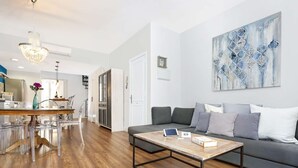 A modern living room with a wooden coffee table, grey sofa, and abstract art on the wall.