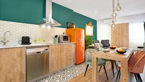Una cucina moderna con mobili in legno, una lavastoviglie in acciaio inossidabile e un frigorifero arancione vintage.