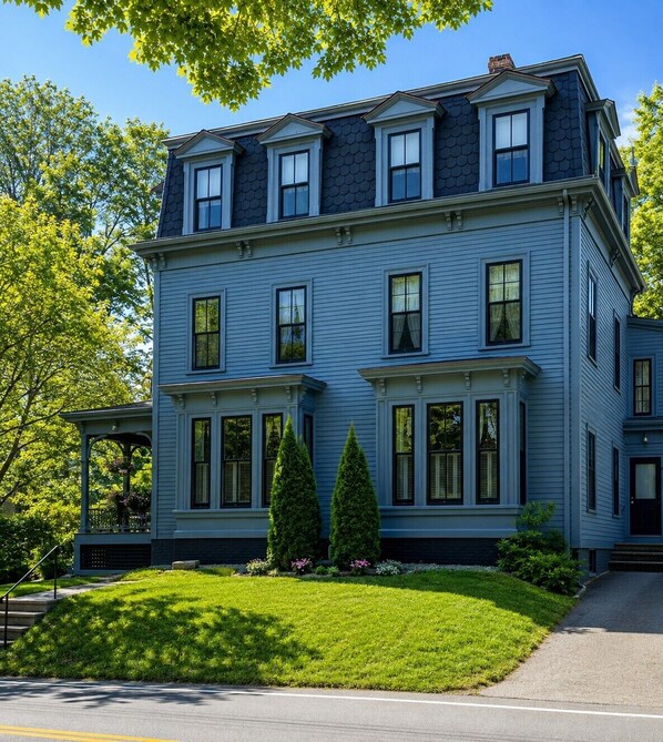 A two-story house with a gabled roof, multiple windows, and a front porch with a railing.