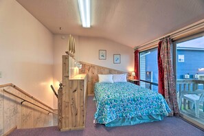 Une chambre à coucher avec un lit, un escalier en bois et une grande fenêtre avec des rideaux.