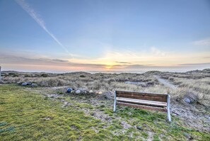 A bench in a natural setting with a sunset in the background. - Sanderling Sea Cottages, Unit 9 with Ocean Views! (Waldport)