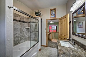A bathroom with a glass-enclosed shower, a sink with a mirror, and a potted plant on the wall. - Sanderling Sea Cottages, Unit 9 with Ocean Views! (Waldport)