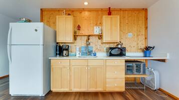 Une cuisine compacte avec des meubles en bois, un réfrigérateur blanc, un four à micro-ondes et une bouilloire.