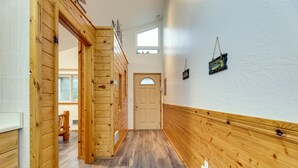A wooden hallway with a door at the end, a window above it, and a small wall-mounted decoration.