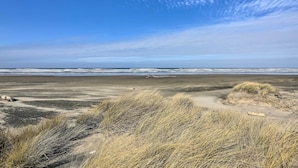 A beach with sand dunes and the ocean in the background.