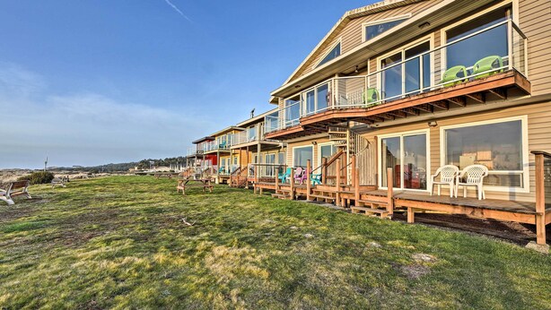 A row of wooden houses with balconies, some with glass railings, and a grassy area with benches and chairs.