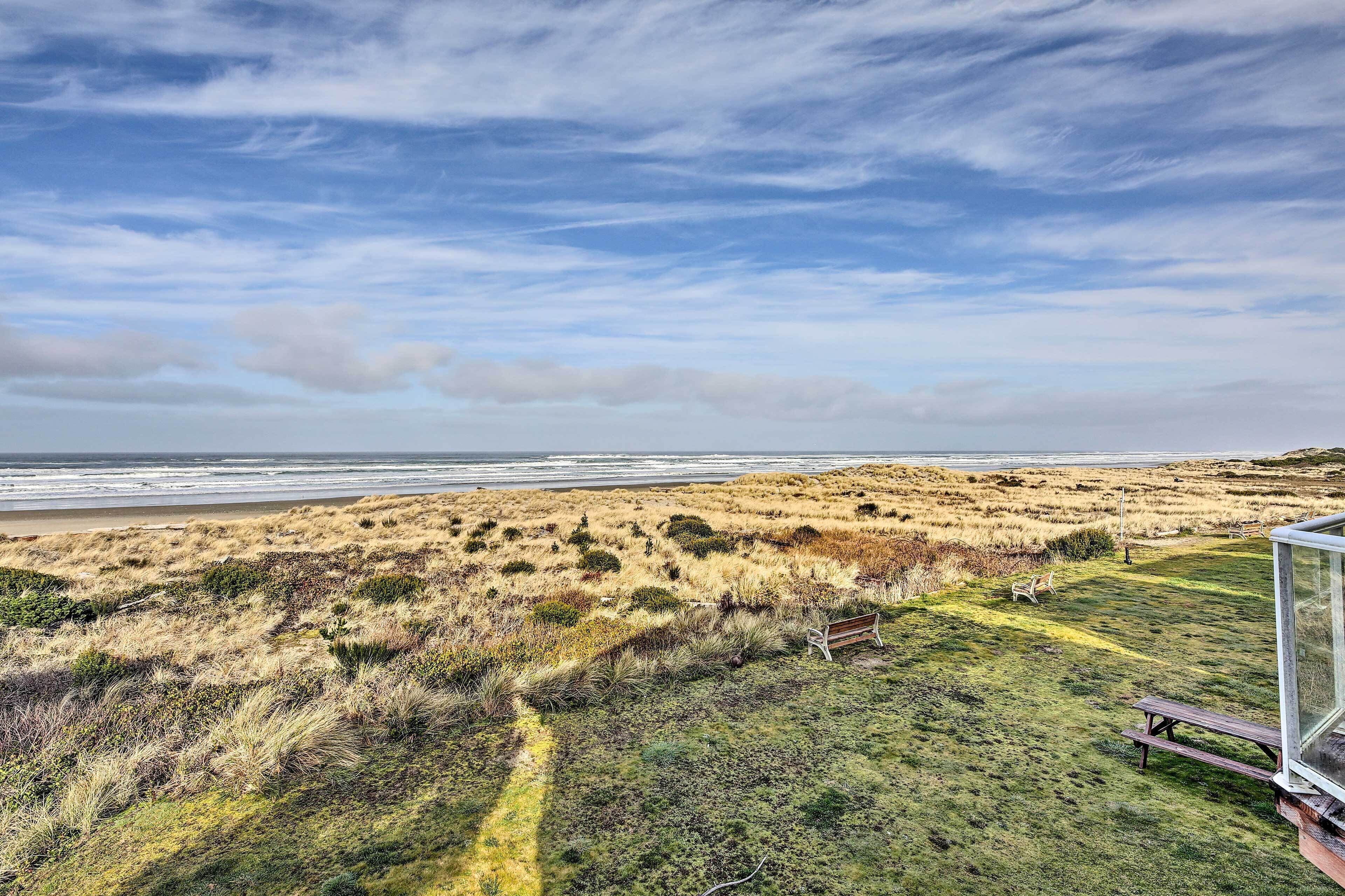 A coastal landscape with a grassy area and a bench overlooking the beach.