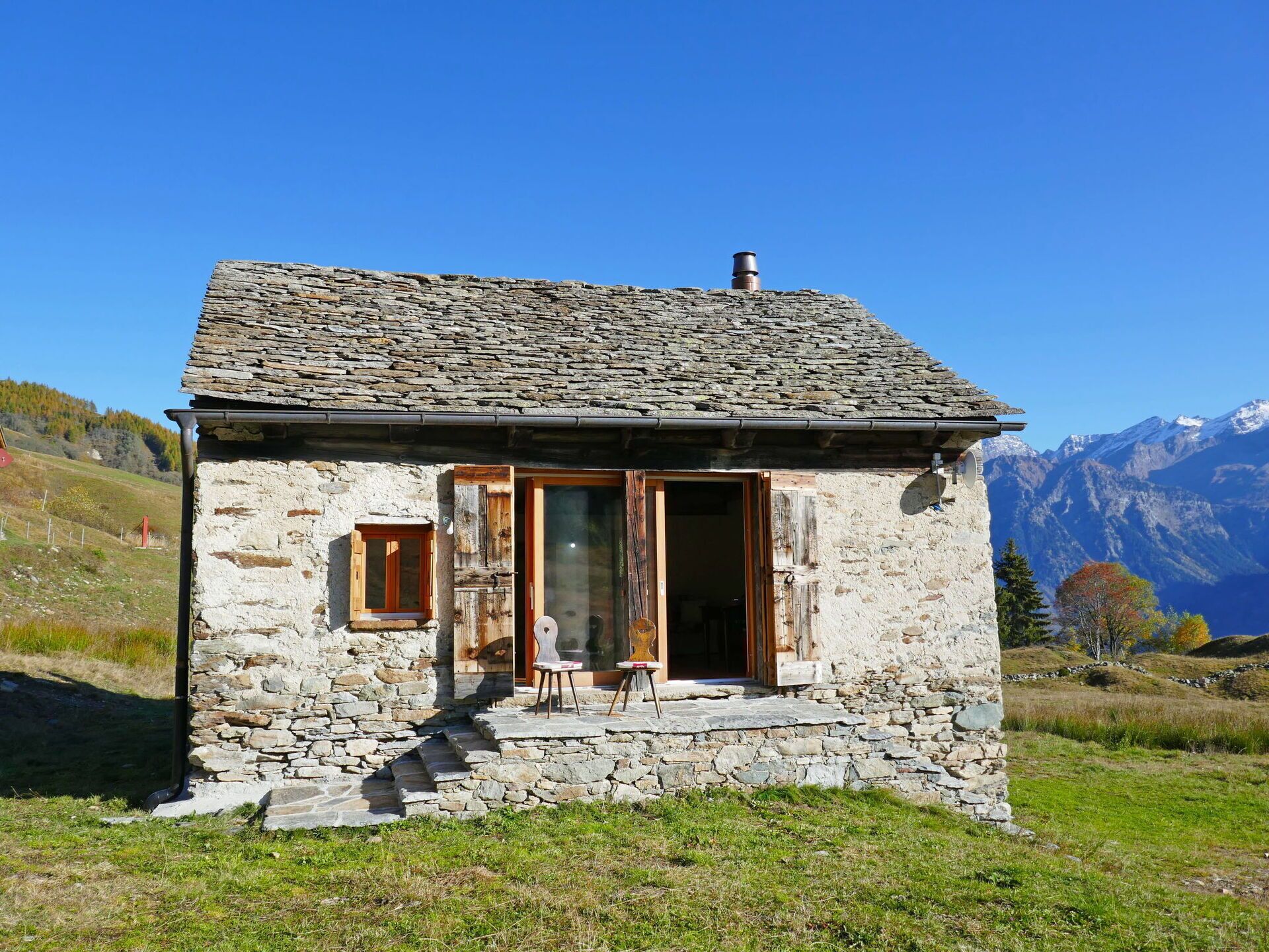 Une petite maison en pierre avec une porte en bois, une petite fenêtre et une cheminée.