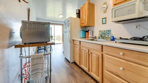 Una cocina con armarios de madera, un microondas, un refrigerador y un escurreplatos.