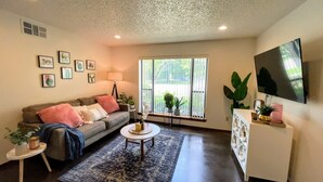 A living room with a sofa, coffee table, and a TV mounted on the wall.