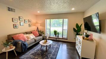 A living room with a sofa, coffee table, and a TV mounted on the wall.