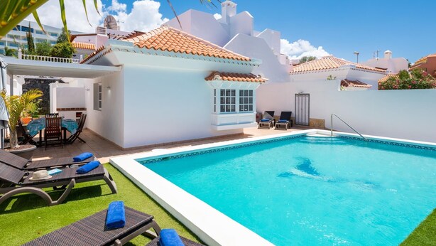 Una piscina amb gandules i una zona de pati coberta.