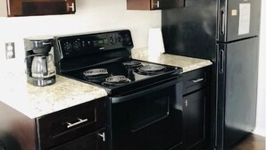 A kitchen with dark wooden cabinets, a black stove, and a black refrigerator.