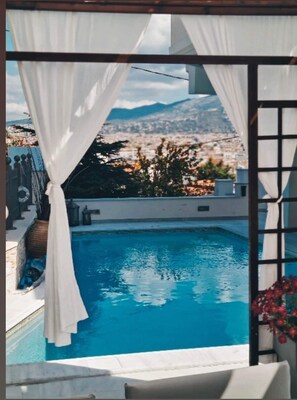 Una piscina amb vista a un paisatge urbà i a les muntanyes.