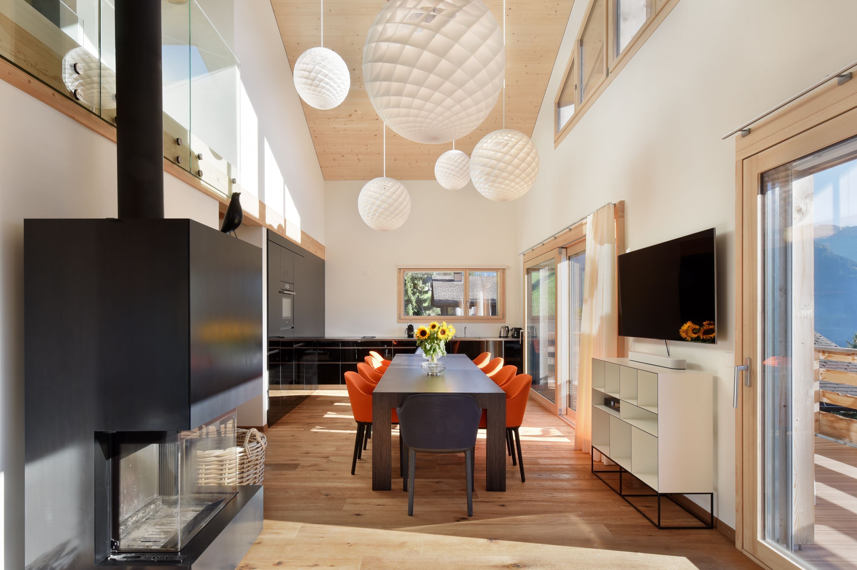 Een moderne keuken met een eethoek, grote ramen en een open haard.